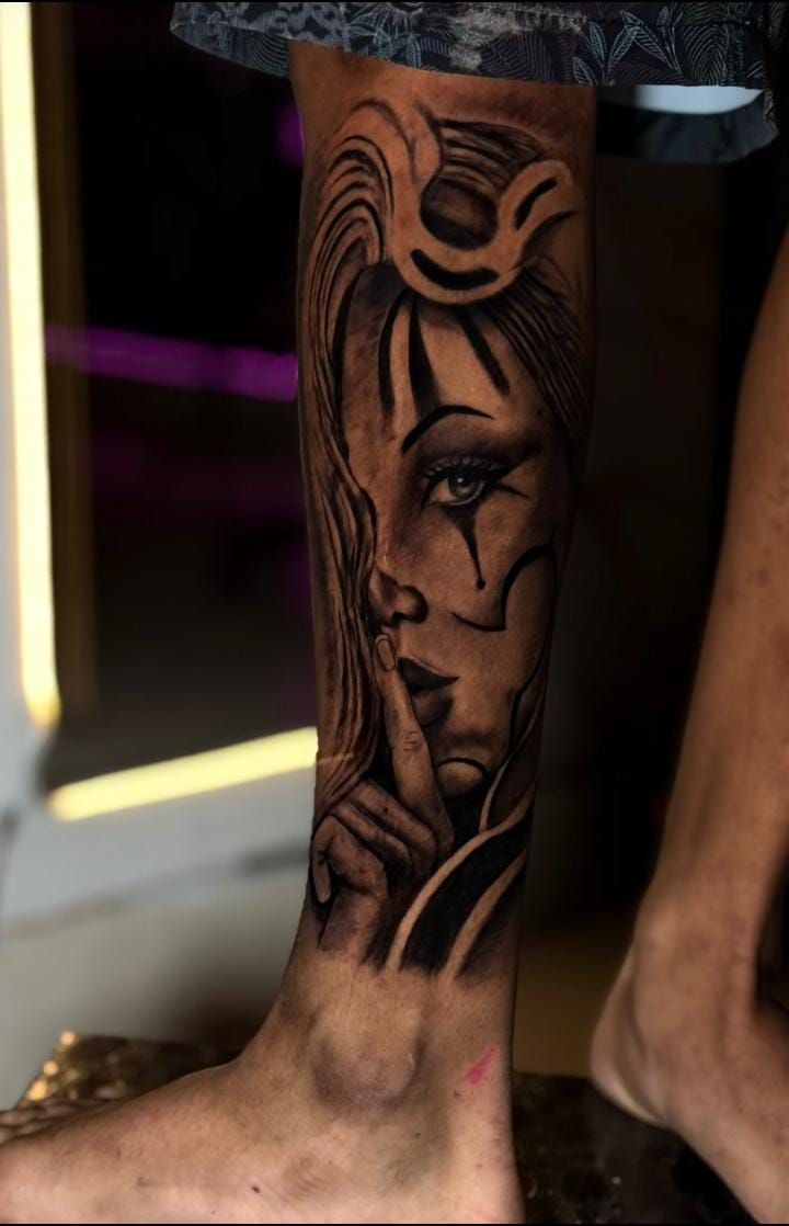 Tatuagem em black and grey de rosto feminino com maquiagem de palhaço, na perna