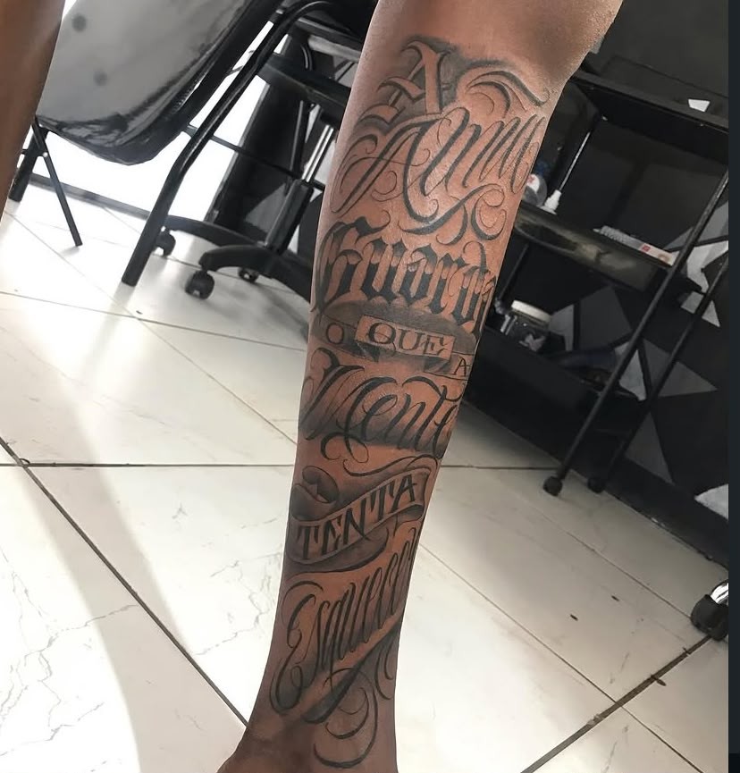 Tatuagem de lettering com faixas na perna